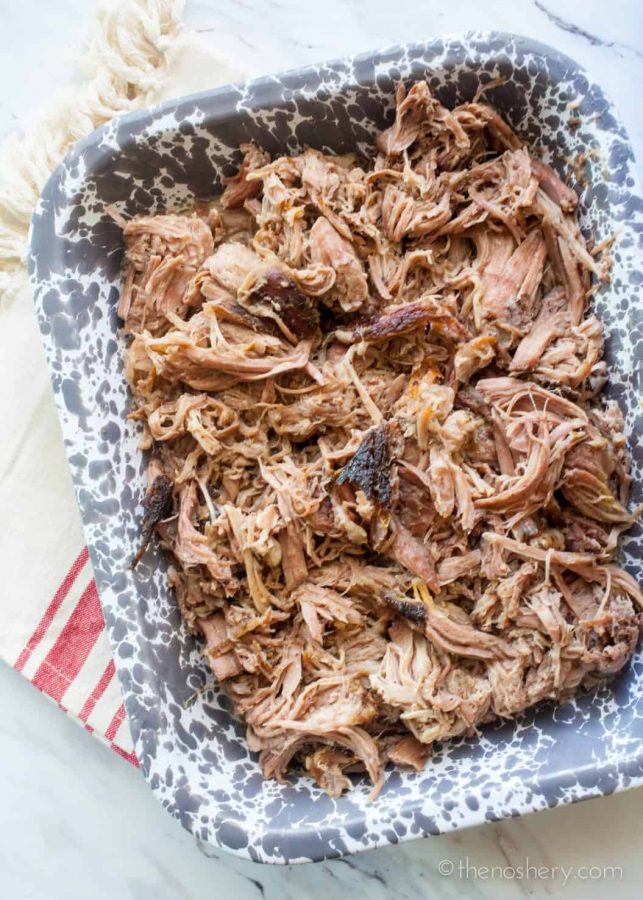 Slow Cooker Pernil (Puerto Rican Pork Shoulder) | Over head view of a grey speckled casserole dish filled with shredded pork.