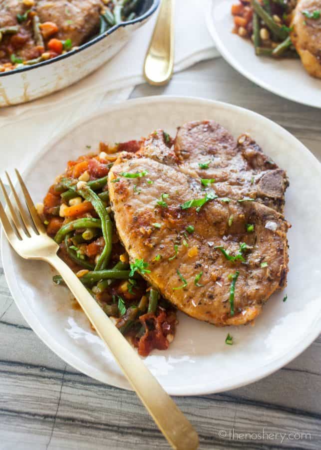 Braised Pork Chops and Garden Vegetables (Chuletas a la Jardinera) | Braised pork chops in a tomato sauce with fresh carrots, corn, & green beans. Resulting in tender pork chops in a sweet and savory sauce & crisp vegetables. | The Noshery