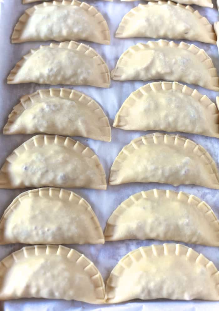 Pastelillos de Carne (Puerto Rican Meat Turnovers) with Homemade Pastelillo Dough Recipe| Two rows of pressed and filled uncooked pastelillos. | The Noshery