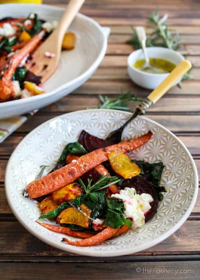 Roasted Beets and Carrots Salad with Burrata | Bowl of roasted carrots, beets, beet greens, and burrata. Platter of salad in the background. | The Noshery