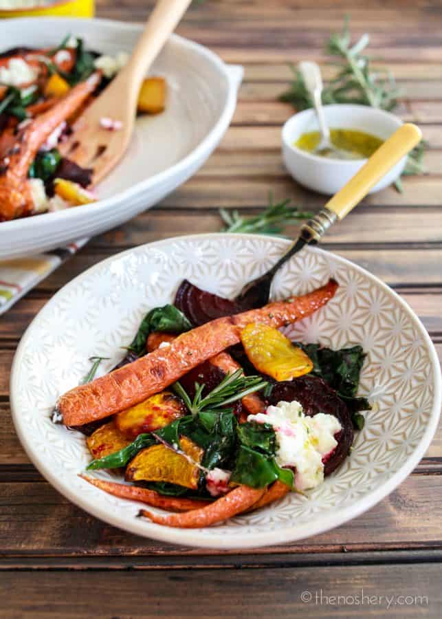 Roasted Beets and Carrots Salad with Burrata | Bowl of roasted carrots, beets, beet greens, and burrata. Platter of salad in the background. | The Noshery