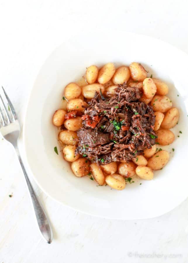 Over head shot of Braised Beef in Red Wine pilled over pan fried gnocchi potato dumplings. | The Noshery