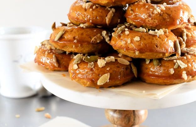 Pumpkin Spiced Donuts with Bourbon Caramel Glaze | A soft and nutty donut packed with pumpkin flavor. But wait, there’s more. I dipped them in a gooey bourbon caramel glaze! | TheNoshery.com