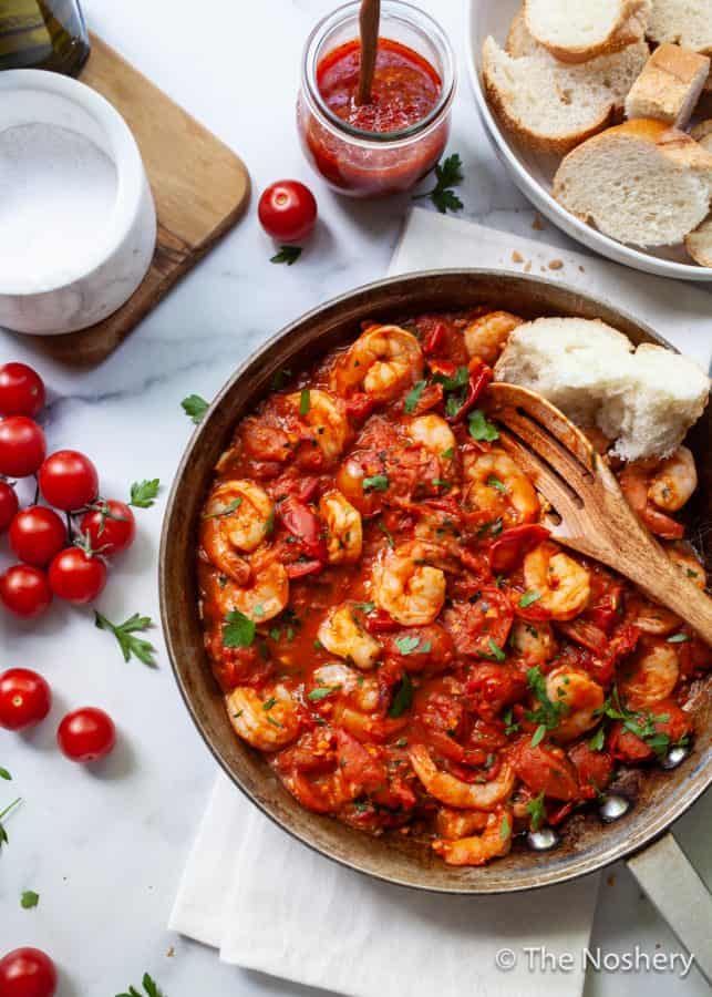 Easy Shrimp Harissa and Tomato Skillet | If you like food that is saucy, spicy and takes 20 minutes to make you will love this skillet. Large shrimp are sautéd in a harissa spiced tomato sauce and served with crusty bread. This harissa and tomato shrimp is also great to toss in pasta or served over polenta. | The Noshery