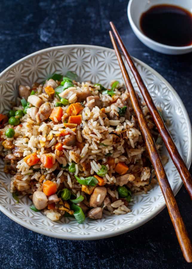 Close up overhead shot of chicken fried rice with chopsticks resting on bowl| The Noshery